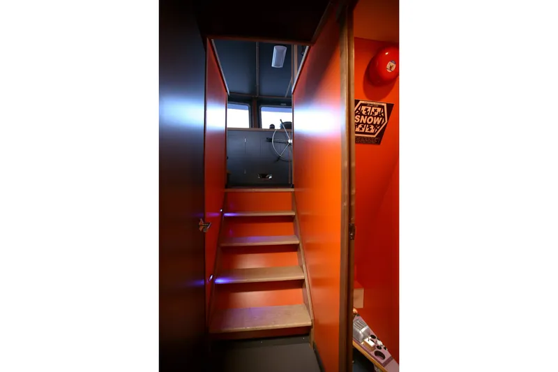 Slide: The Image of Interior stairs of a 1974 Custom Steel Cannery Tender, featuring vibrant orange walls. - 5