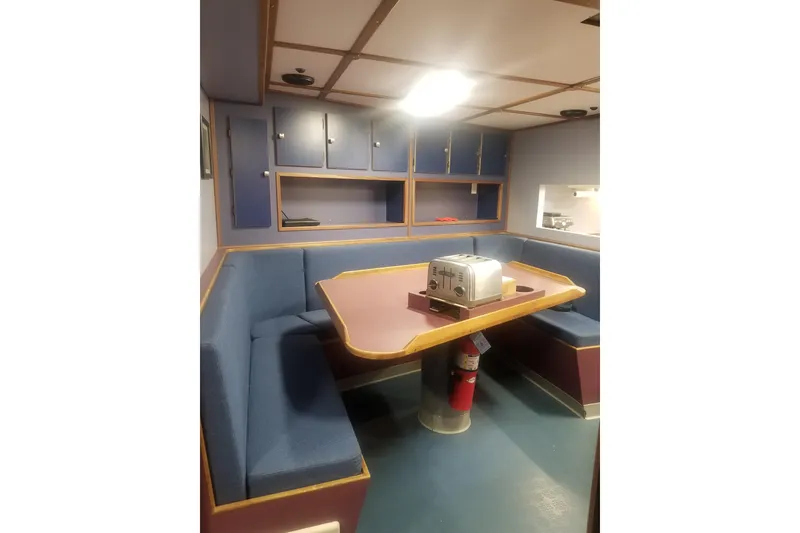 Slide: The Image of 1974 Custom Steel Cannery Tender interior with blue seating, table, and toaster. - 8