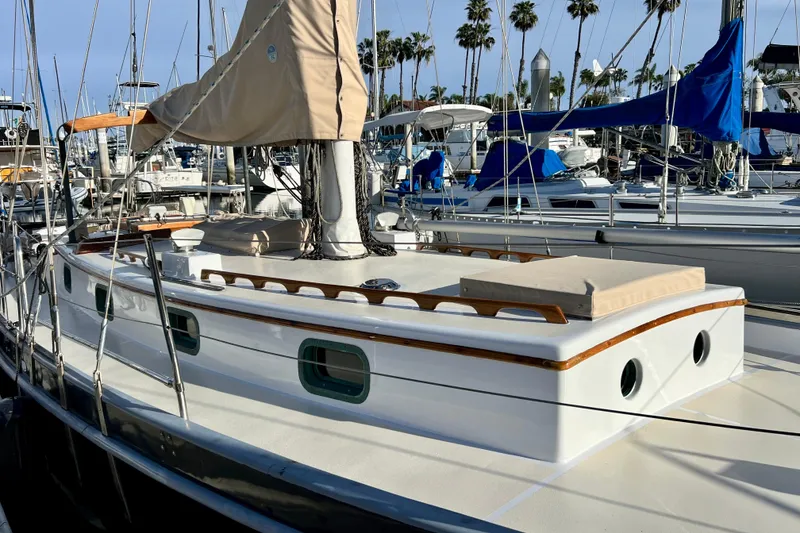 Slide: The Image of 1975 Cape George 36 sailboat docked in marina, surrounded by other boats and palm trees. - 15