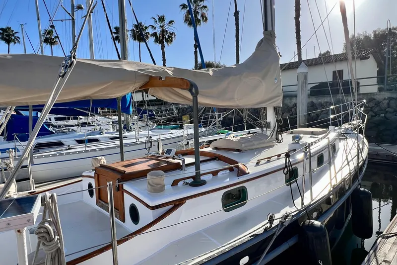 Slide: The Image of 1975 Cape George 36 sailboat docked in marina, surrounded by other boats and palm trees. - 16
