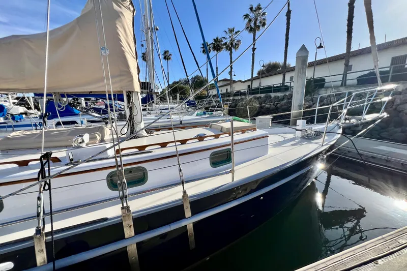Slide: The Image of 1975 Cape George 36 sailboat docked in marina, surrounded by palm trees and clear sky. - 17