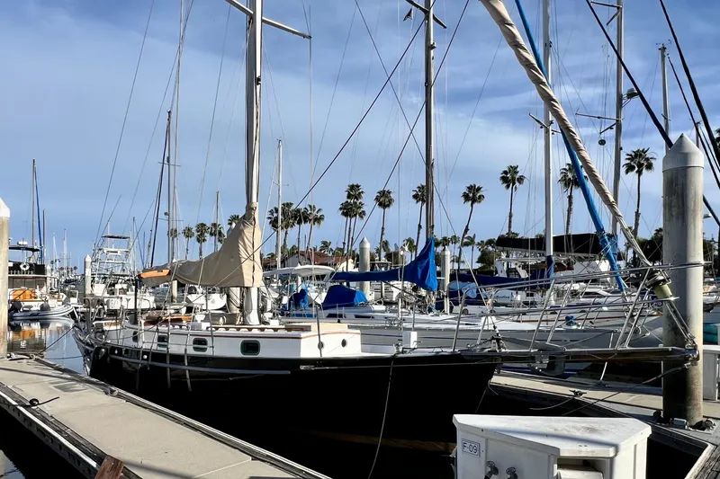Slide: The Image of 1975 Cape George 36 sailboat docked in a marina with palm trees in the background. - 2
