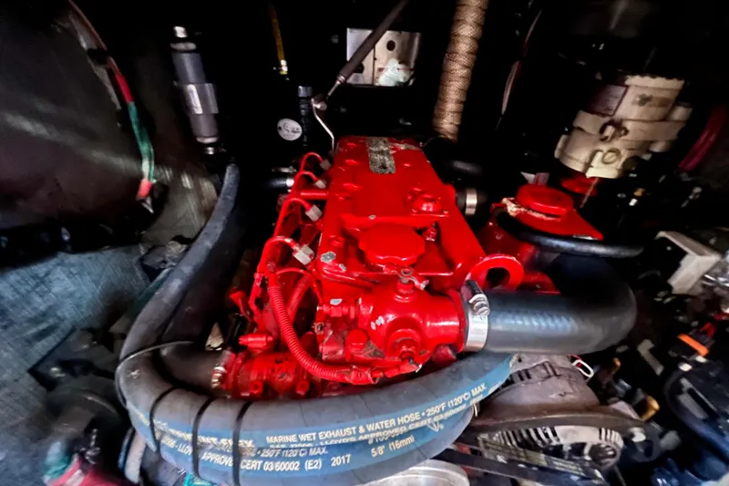 Slide: The Image of Engine of a 1975 Cape George 36 sailboat, featuring red components and marine hoses. - 76