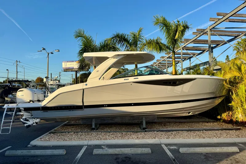 The Image of 2026 Four Winns H33 OB boat displayed outdoors with palm trees in the background. - 1