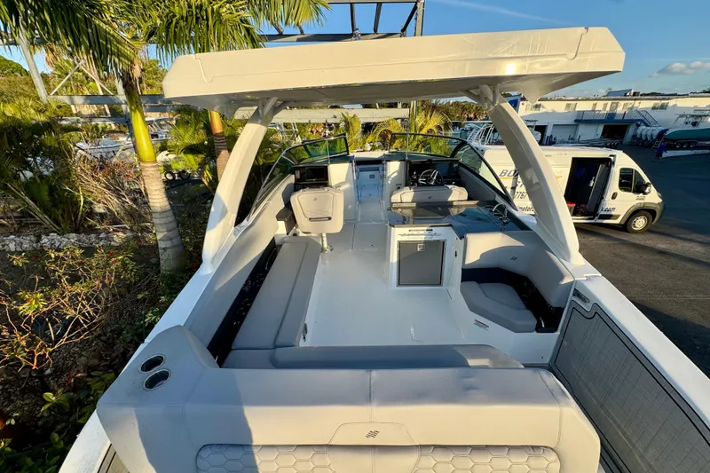 Slide: The Image of 2026 Four Winns H33 OB boat with spacious seating and modern design, docked near palm trees. - 12