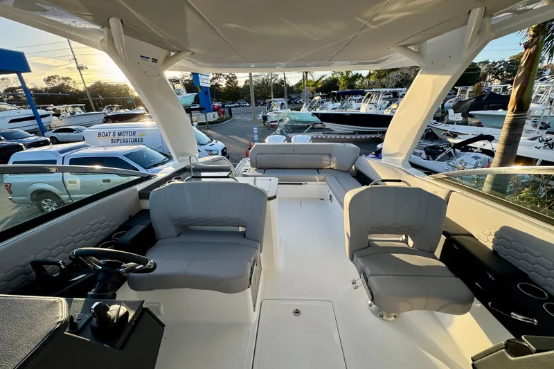 Slide: The Image of 2026 Four Winns H33 OB boat interior with seating and steering wheel at a dealership. - 26