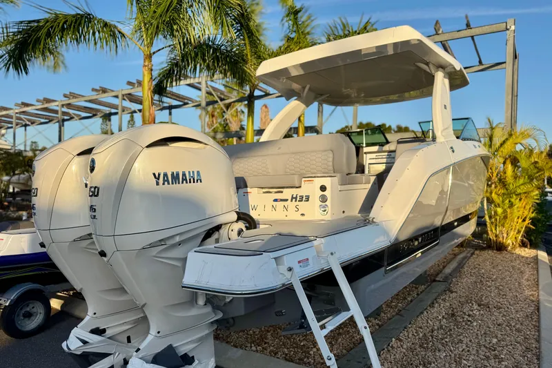 Slide: The Image of 2026 Four Winns H33 OB boat with Yamaha engines, docked under palm trees. - 5