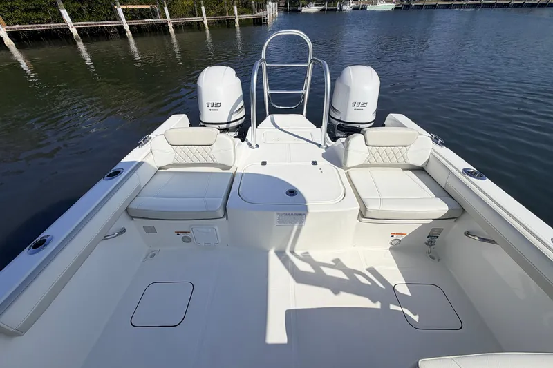 Slide: The Image of 2026 World Cat 230 DC boat interior with dual Yamaha 115 engines, docked on calm water. - 10