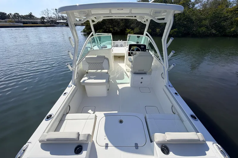 Slide: The Image of 2026 World Cat 230 DC boat interior with seating and helm, docked on calm water. - 11