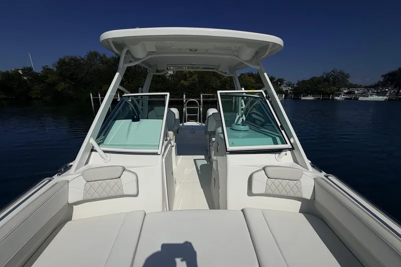 Slide: The Image of 2026 World Cat 230 DC boat interior with open windshield, docked on calm water. - 13