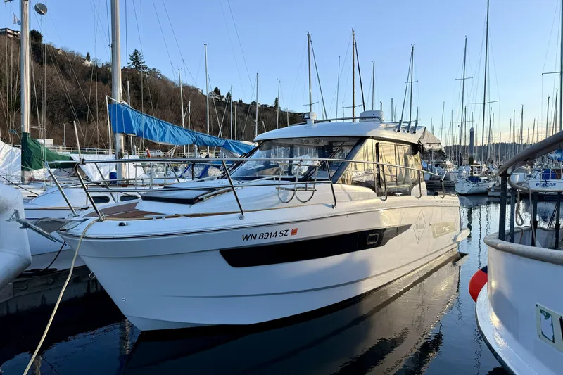 Slide: The Image of 2022 Jeanneau NC Weekender 895 docked in a marina, surrounded by sailboats. - 14