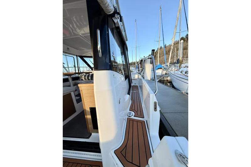 Slide: The Image of 2022 Jeanneau NC Weekender 895 docked, showcasing sleek design and wooden deck details. - 18