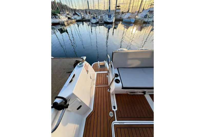 Slide: The Image of 2022 Jeanneau NC Weekender 895 docked, showcasing elegant deck and serene marina view. - 19