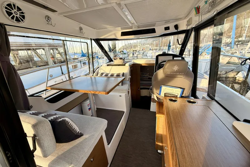 Slide: The Image of Interior of 2022 Jeanneau NC Weekender 895, featuring seating, table, and helm station. - 22