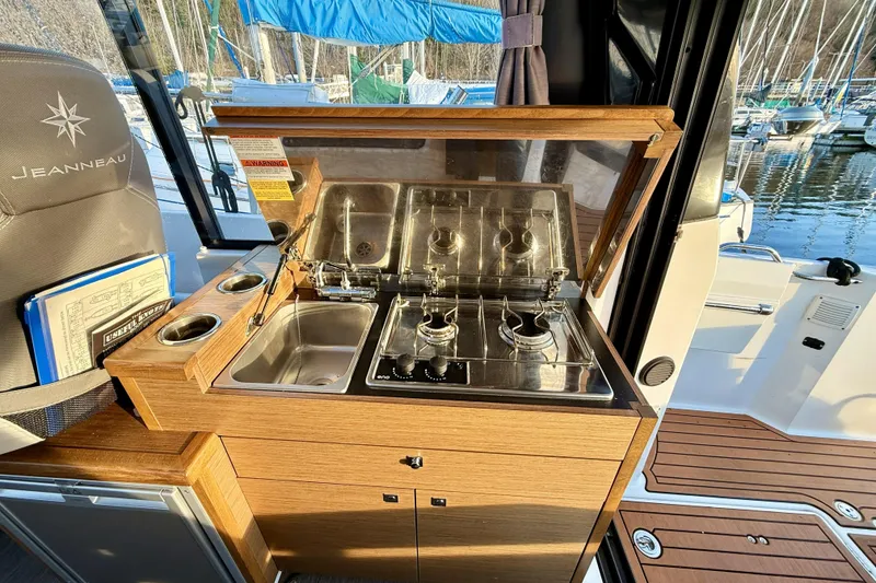 Slide: The Image of 2022 Jeanneau NC Weekender 895 boat kitchen with stove and sink, docked at marina. - 25