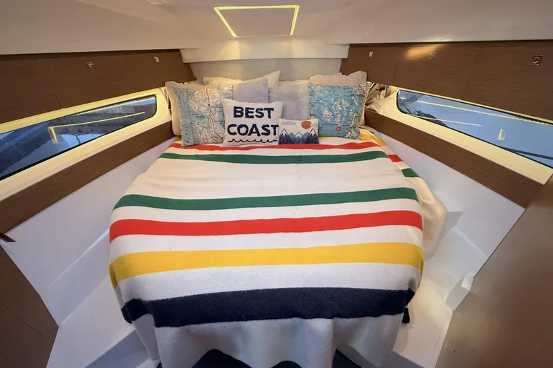 Slide: The Image of Cozy cabin interior of 2022 Jeanneau NC Weekender 895 with colorful bedding and decorative pillows. - 33