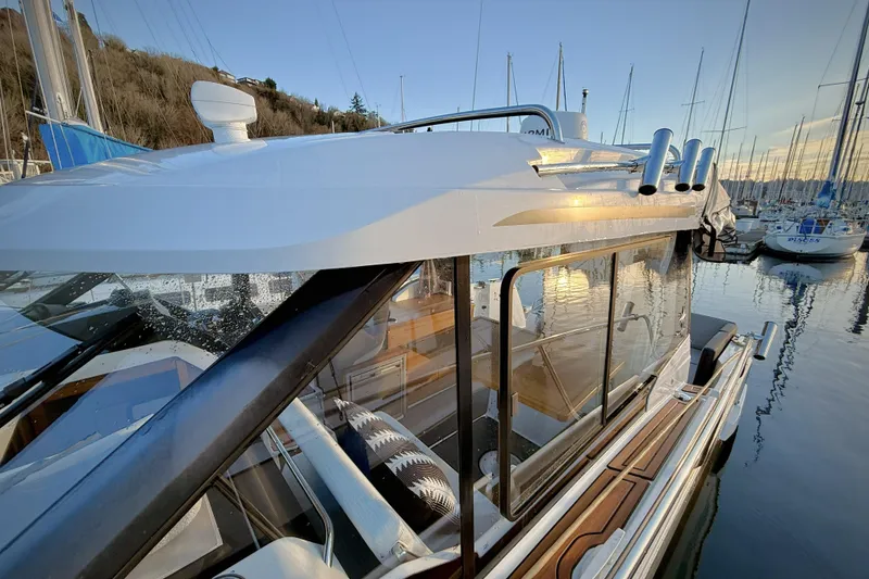 Slide: The Image of 2022 Jeanneau NC Weekender 895 docked at marina, reflecting serene waters and surrounding boats. - 44