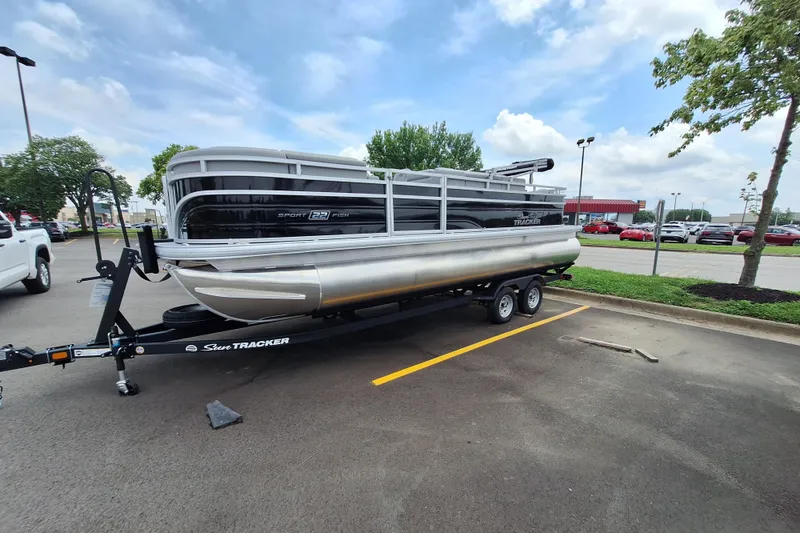 Slide: The Image of 2026 Sun Tracker SportFish 22 DLX pontoon boat on trailer in parking lot. - 2