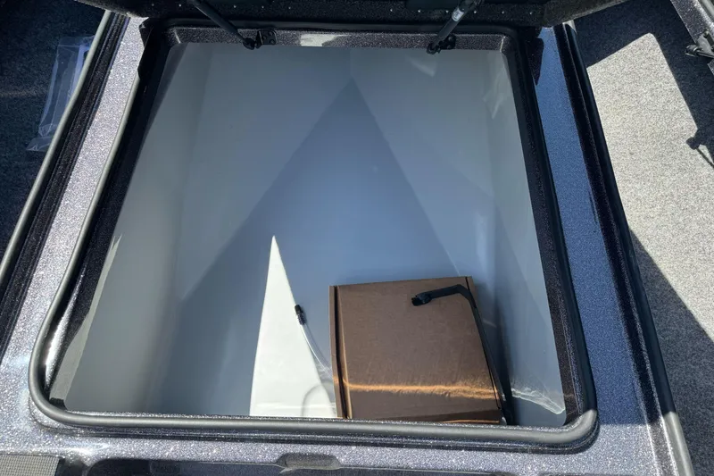 Slide: The Image of Open storage compartment in 2026 Triton 18 TrX boat, featuring a cardboard box inside. - 10