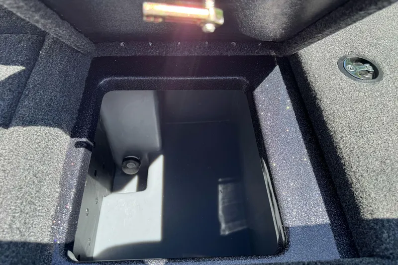 Slide: The Image of Open storage compartment in 2026 Triton 18 TrX boat, featuring carpeted interior. - 17