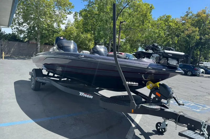 Slide: The Image of 2026 Triton 18 TrX boat on trailer in parking lot, surrounded by trees. - 2