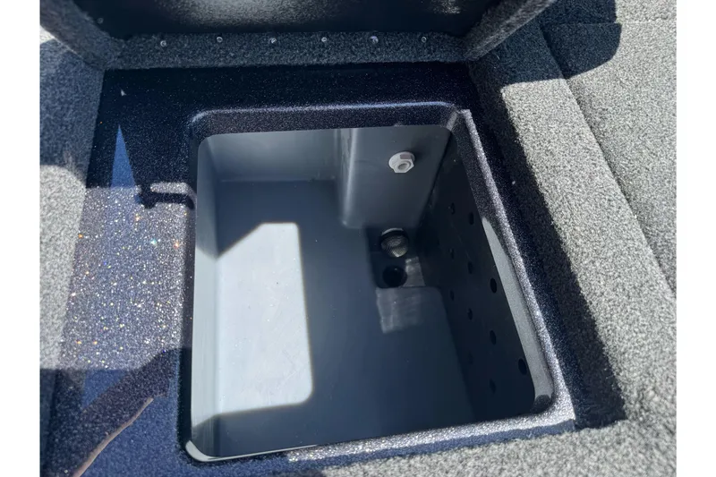 Slide: The Image of Open storage compartment in 2026 Triton 18 TrX boat, featuring a sleek, carpeted interior. - 18