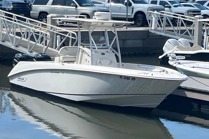 Slide: The Image of 2007 Boston Whaler 270 Outrage boat docked at marina with vehicles in background. - 5