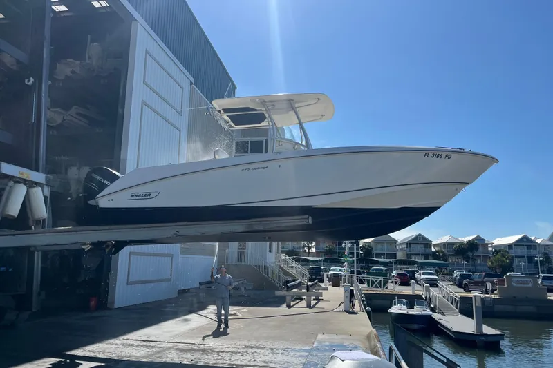Slide: The Image of 2007 Boston Whaler 270 Outrage being lifted at a marina under clear blue skies. - 6