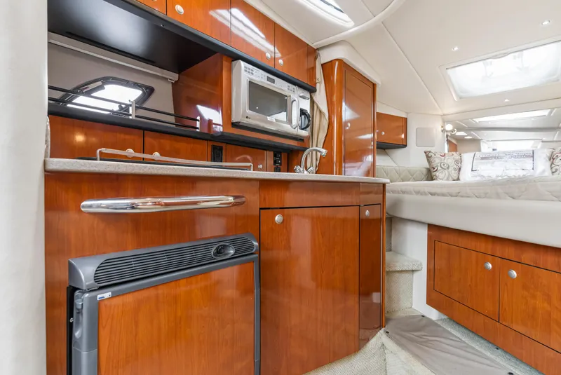 Slide: The Image of 2007 Sea Ray 310 Sundancer interior with kitchenette, featuring wood cabinetry and modern appliances. - 10