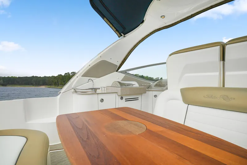 Slide: The Image of 2007 Sea Ray 310 Sundancer interior with wooden table and seating, overlooking water. - 17