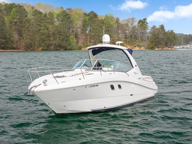 Slide: The Image of 2007 Sea Ray 310 Sundancer boat on a scenic lake with forested shoreline. - 2