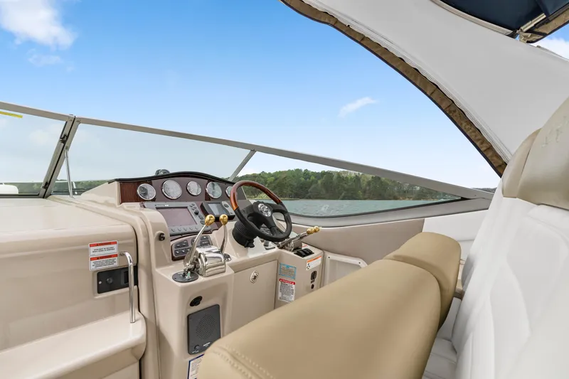 Slide: The Image of 2007 Sea Ray 310 Sundancer helm with beige seating and modern controls, overlooking serene waters. - 21