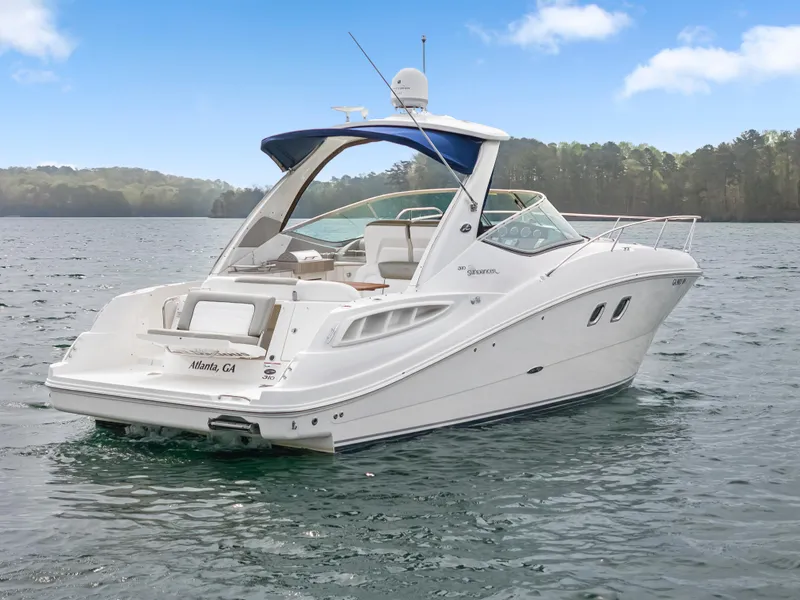 Slide: The Image of 2007 Sea Ray 310 Sundancer boat on a serene lake with forested background. - 4