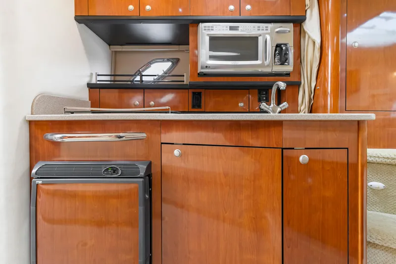 Slide: The Image of 2007 Sea Ray 310 Sundancer galley with wood cabinetry, microwave, and compact fridge. - 7