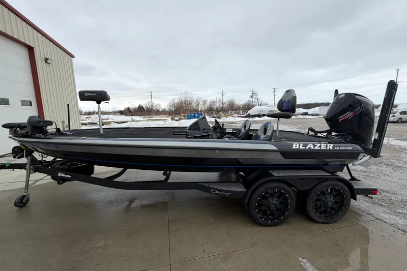 The Image of 2023 Blazer 650 Pro Tour boat on trailer, parked outdoors near a building. - 0