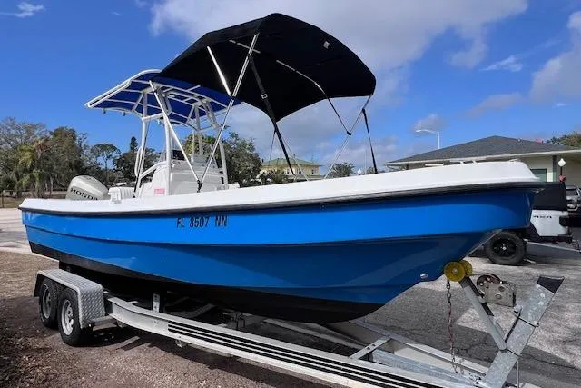 Slide: The Image of 2008 Angler PANGA 22 boat on trailer, blue hull, black canopy, parked outdoors. - 5