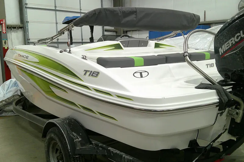 Slide: The Image of 2023 Tahoe T18 boat with green accents in a garage setting. - 2