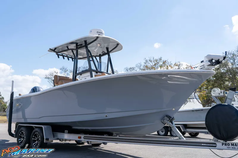 The Image of 2021 Sea Hunt Ultra 229 boat on trailer, displayed outdoors under clear sky. - 1