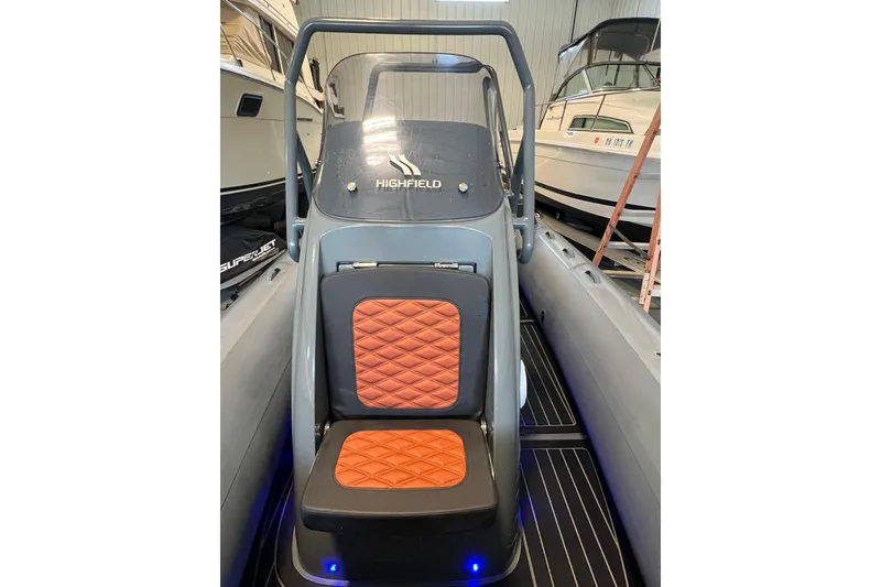 Slide: The Image of 2024 Highfield Sport 560 boat interior with orange quilted seats in a showroom. - 16
