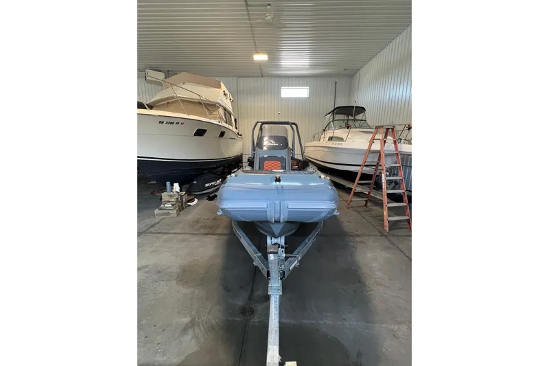 Slide: The Image of 2024 Highfield Sport 560 boat in storage, surrounded by other boats and a ladder. - 5