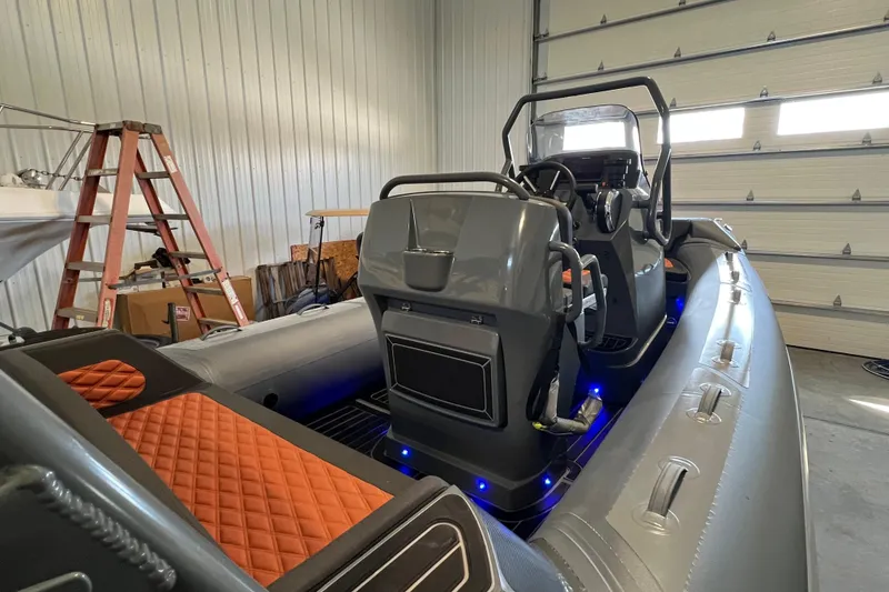 Slide: The Image of 2024 Highfield Sport 560 boat interior with orange quilted seats in a garage setting. - 9