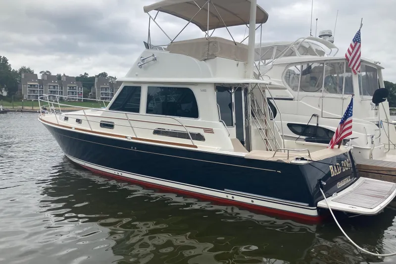 Slide: The Image of 2021 Sabre 42 Fly Bridge yacht docked, featuring sleek design and American flag. - 2