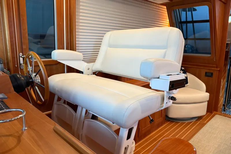 Slide: The Image of Captain's chair on 2021 Sabre 42 Fly Bridge, featuring luxurious white upholstery and wooden accents. - 64