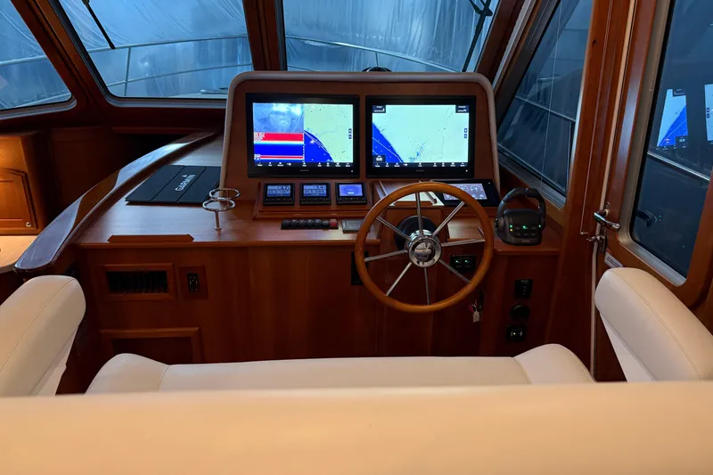 Slide: The Image of 2021 Sabre 42 Fly Bridge helm with dual navigation screens and wooden steering wheel. - 65