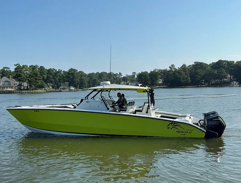 Slide: The Image of 2020 Prowler 42 boat with vibrant green hull cruising on a calm lake. - 2