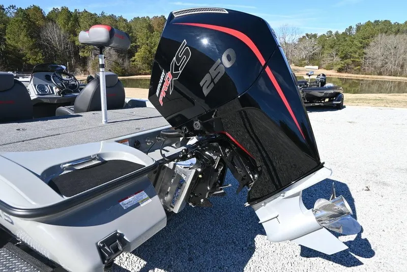 Slide: The Image of 2025 Caymas 201 Pro boat with powerful 250 HP engine, parked on gravel near a lake. - 3