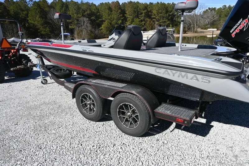 Slide: The Image of 2025 Caymas 201 Pro boat on trailer, parked on gravel, surrounded by trees. - 5