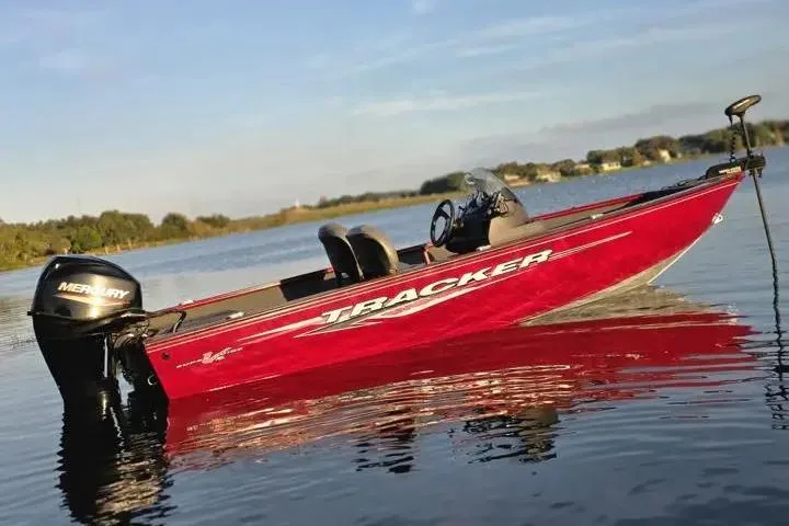 Slide: The Image of 2021 Tracker Super Guide V-16 SC boat on calm lake water, featuring a Mercury engine. - 11