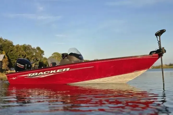 Slide: The Image of 2021 Tracker Super Guide V-16 SC boat on calm water, red exterior, clear sky. - 12