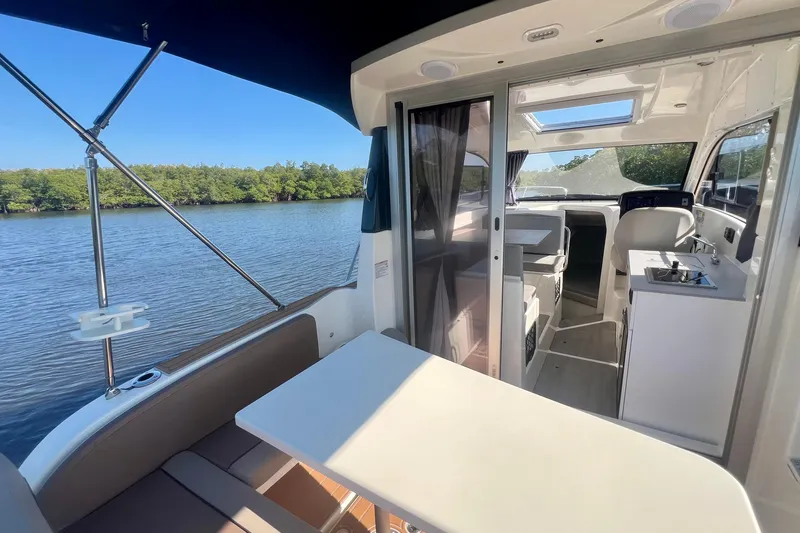 Slide: The Image of 2024 Bayliner Trophy T25 Explorer interior with seating, table, and water view. - 15